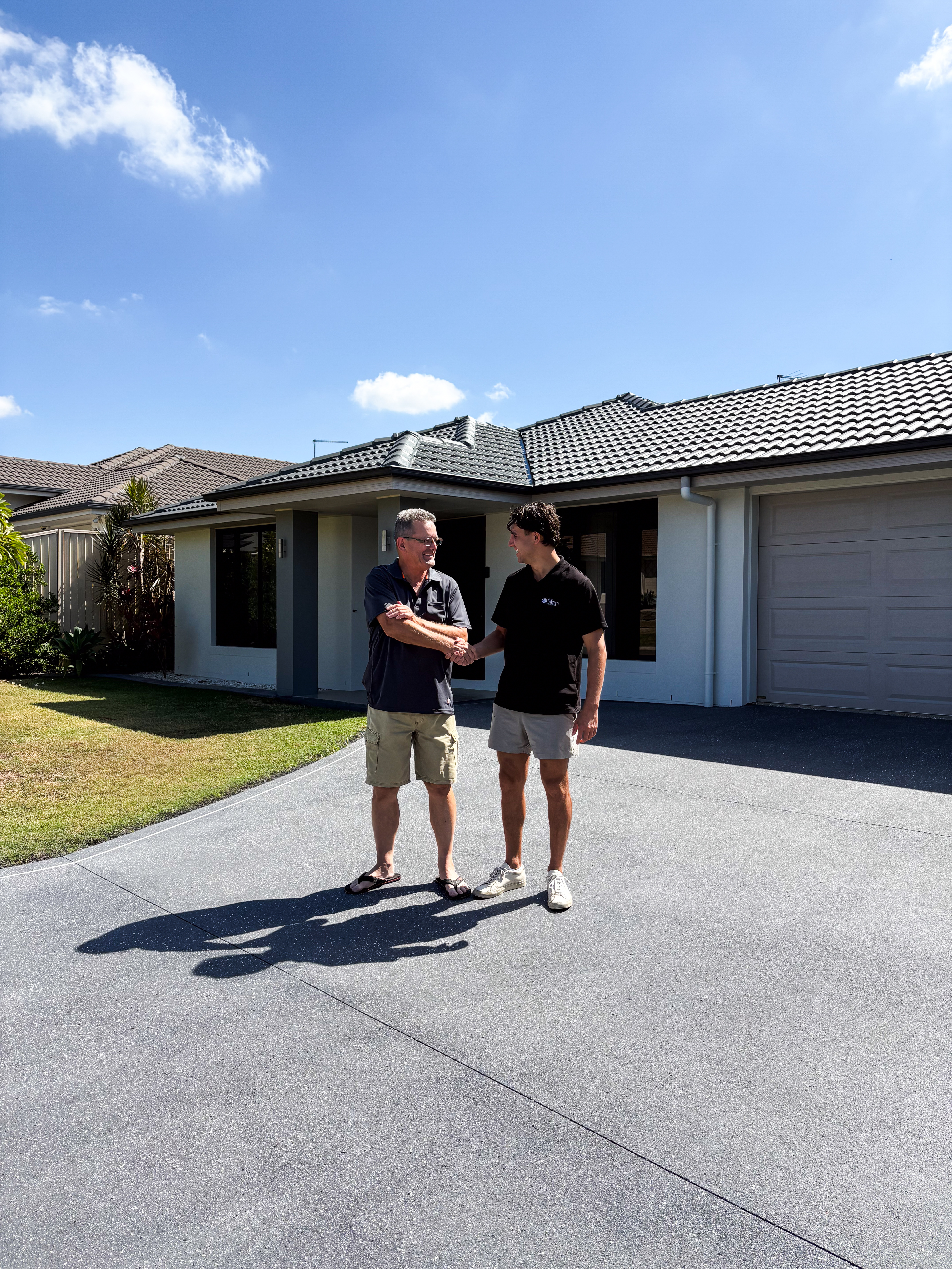 Lachlan shaking hands with a happy customer on a freshly sealed driveway